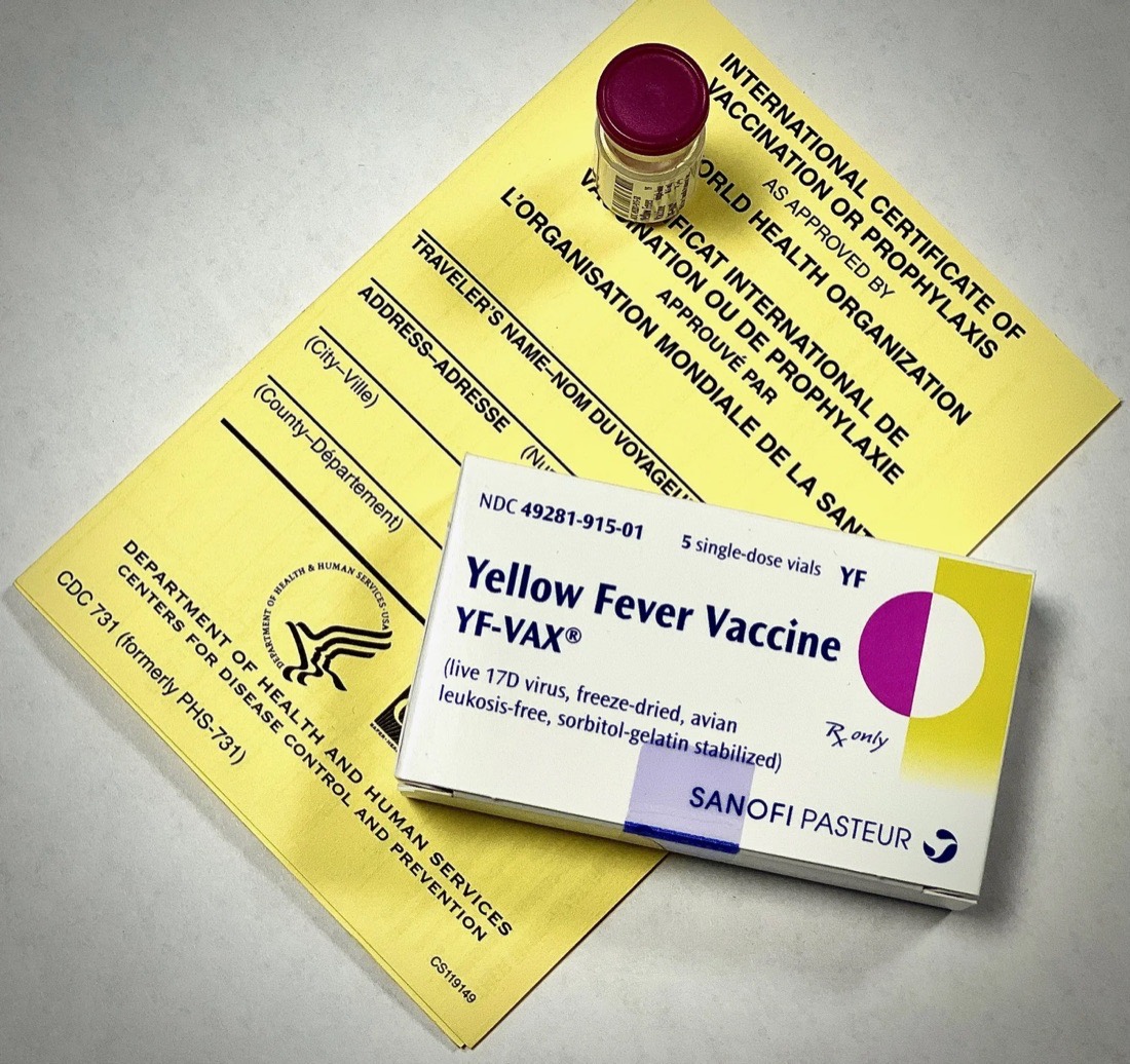Yellow fever vaccine box and vial resting on an International Certificate of Vaccination, the yellow card